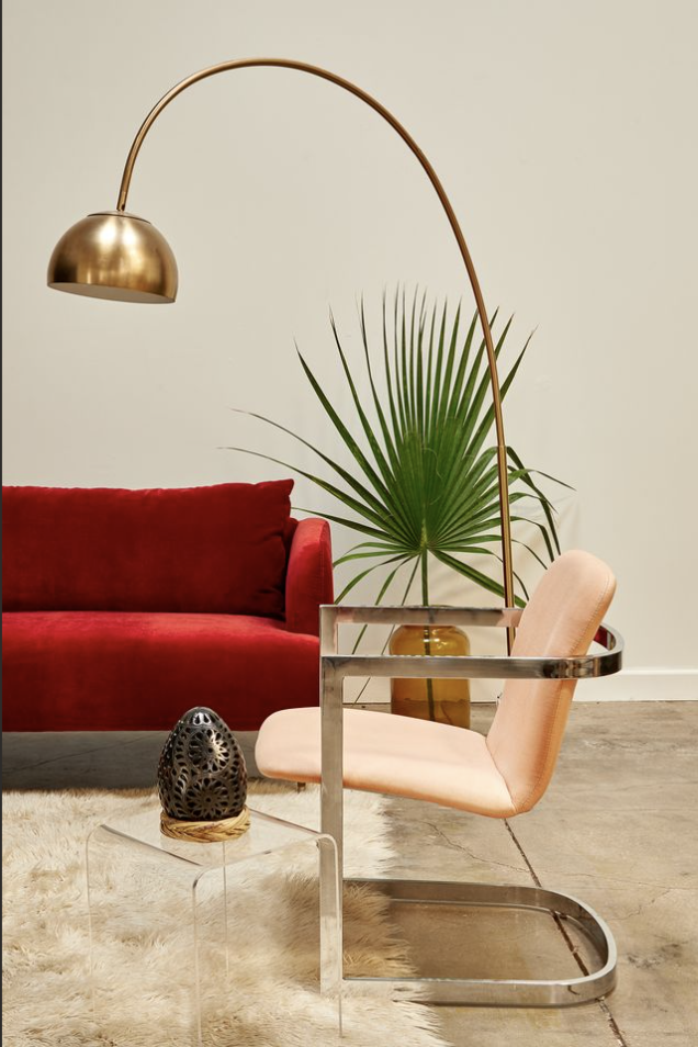 Sculptural brass lamp, red velvet sofa, and artisan-made pottery