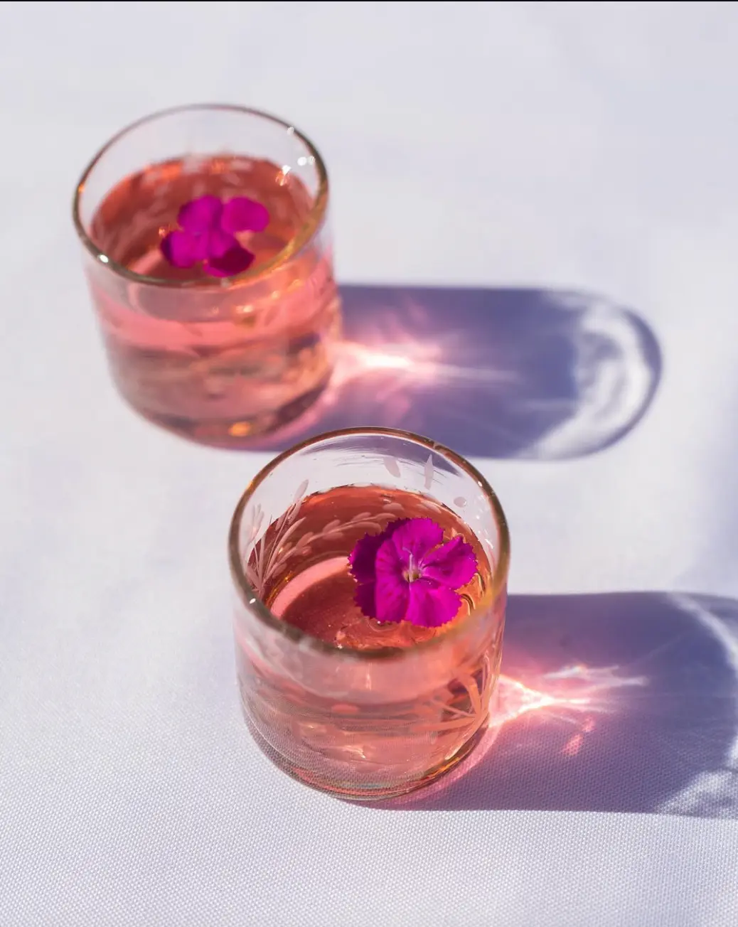 Handblown rose glasses casting soft shadows